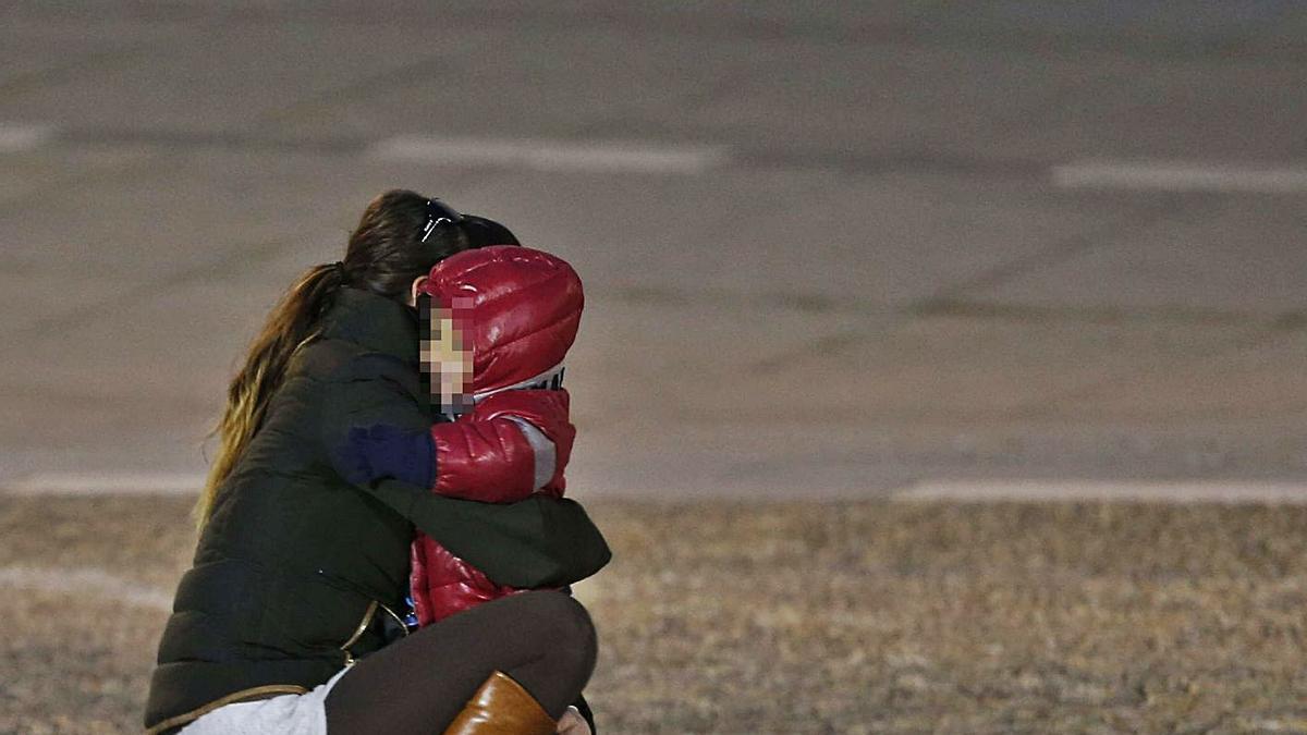 Una madre se abraza con un pequeño en la vía pública.