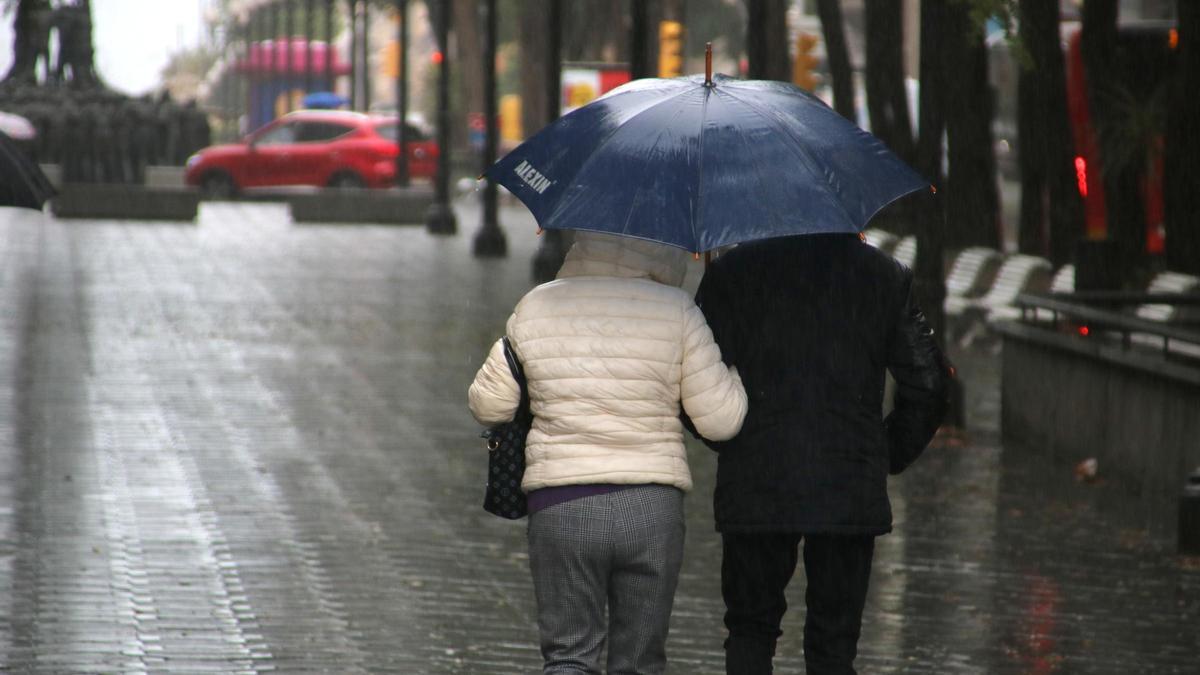 Dues persones caminen sota la pluja, en una imatge d'arxiu
