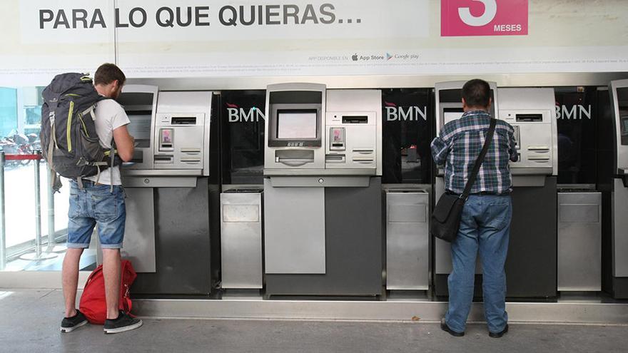 Dos clientes usan los cajeros en la sede central de Cajamurcia en la Gran Vía de Murcia.