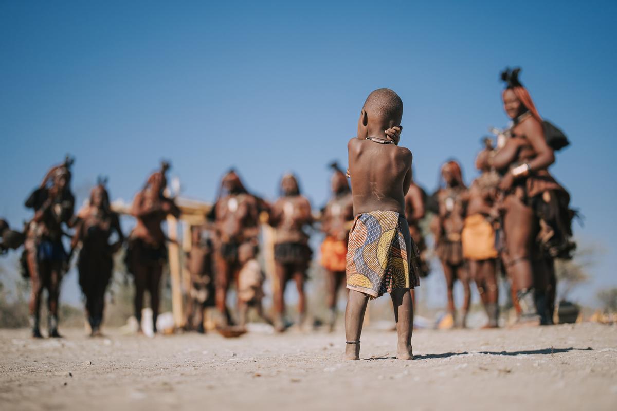 Niño himba namibio mirando a los aldeanos.