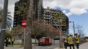 Unos bomberos, junto al edificio siniestrado en Valencia.
