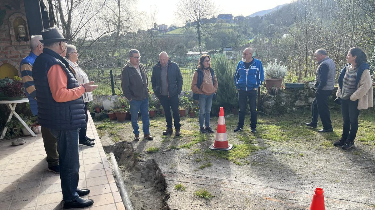 Los vecinos ante una de las zanjas abiertas ante una de las viviendas de La Piñera