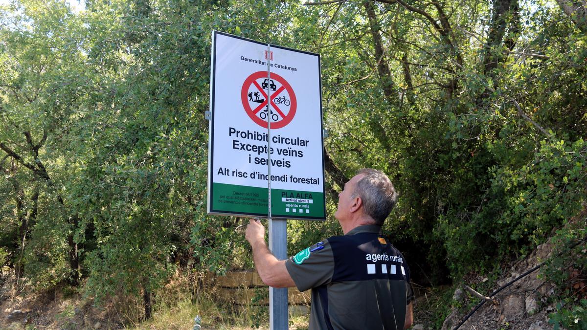 Un Agent Rural obre un cartell de prohibició del pas al Montsec a la zona de Corçà, a Àger, per l'activació del pla Alfa 3