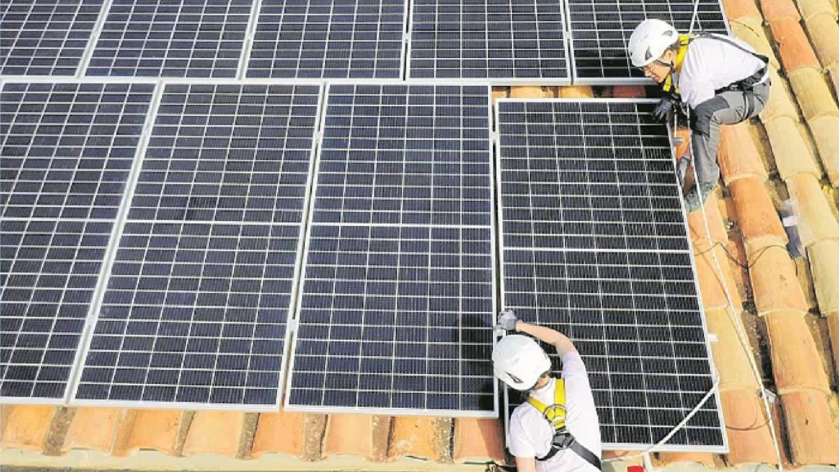 Unos operarios instalan unas placas solares en el teja de una vivienda para beneficiarse de la energía que brinda el sol.