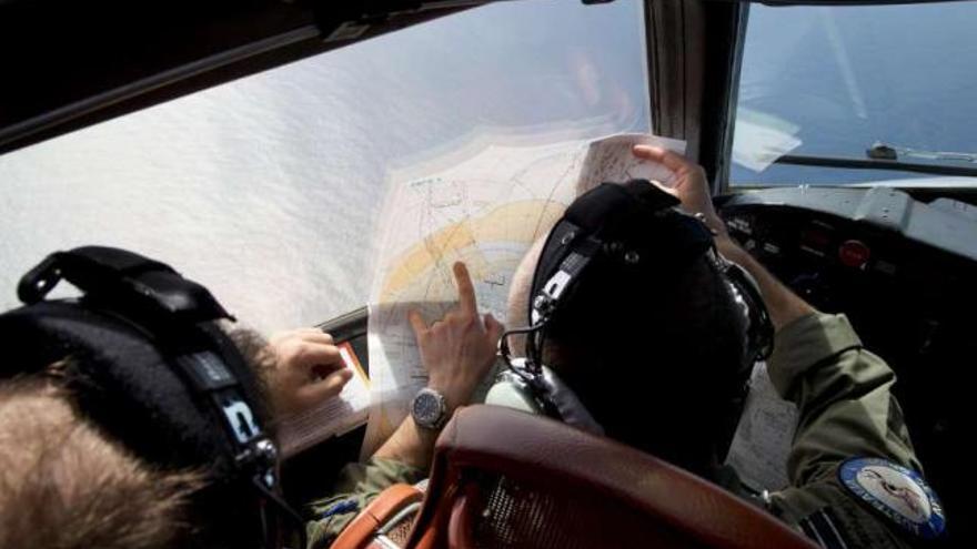 Dos tripulantes de un avión observan un mapa durante los rastreos por aguas del océano Índico. / michael martina