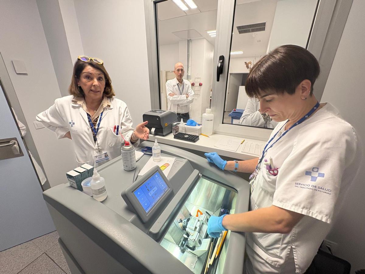 Ana María Gutiérrez, a la izquierda, y Bárbara Fernández Hevia junto al criostato. Tras el cristal, Álvaro Iglesias