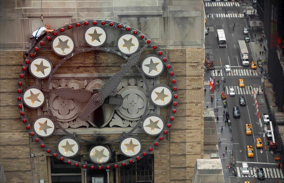 Un trabajador se sube a un reloj para reemplazar bombillas en el edificio Paramount en Times Square en Nueva York