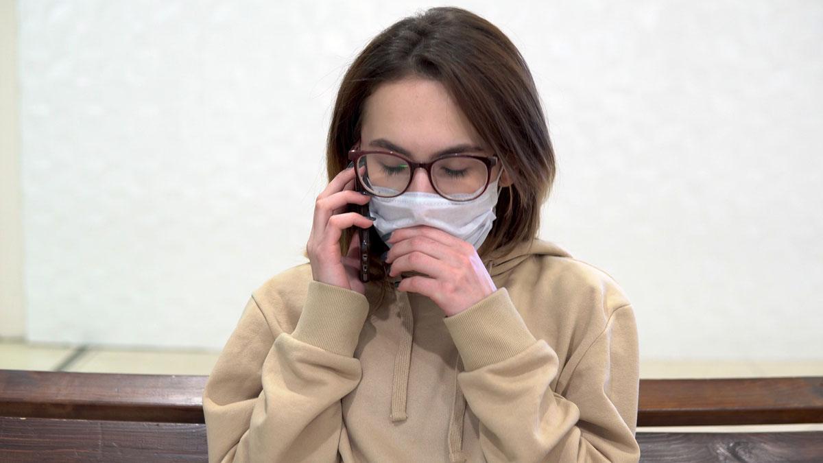 Una mujer tose mientras habla con el móvil