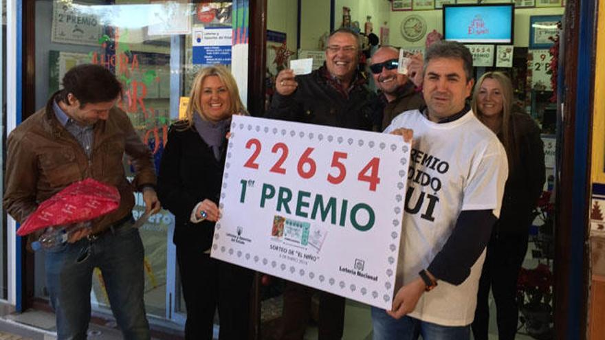 Pedro Tomé Martínez y Sabrina Borghi, sostienen el cartel con el número premiado en el Niño, vendido en Playamar.