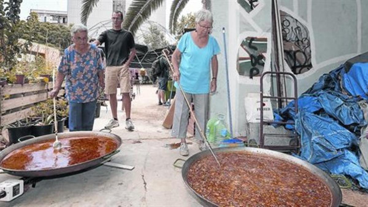 Unas vecinas cocinan dos paellas en el solar de Germanetes, en el Eixample.