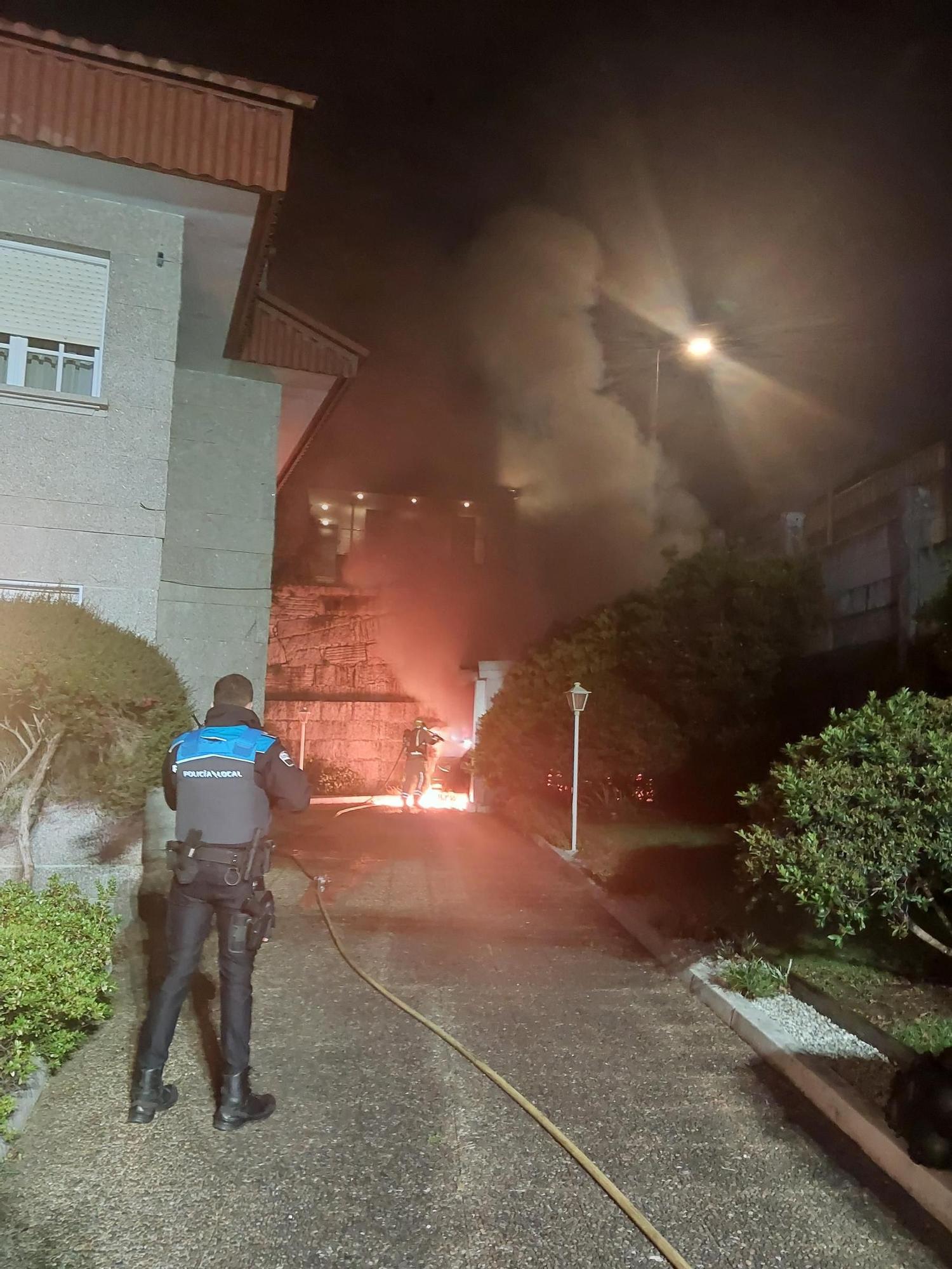 La Policía de Moaña sofocando el fuego del coche en la finca de Tirán.