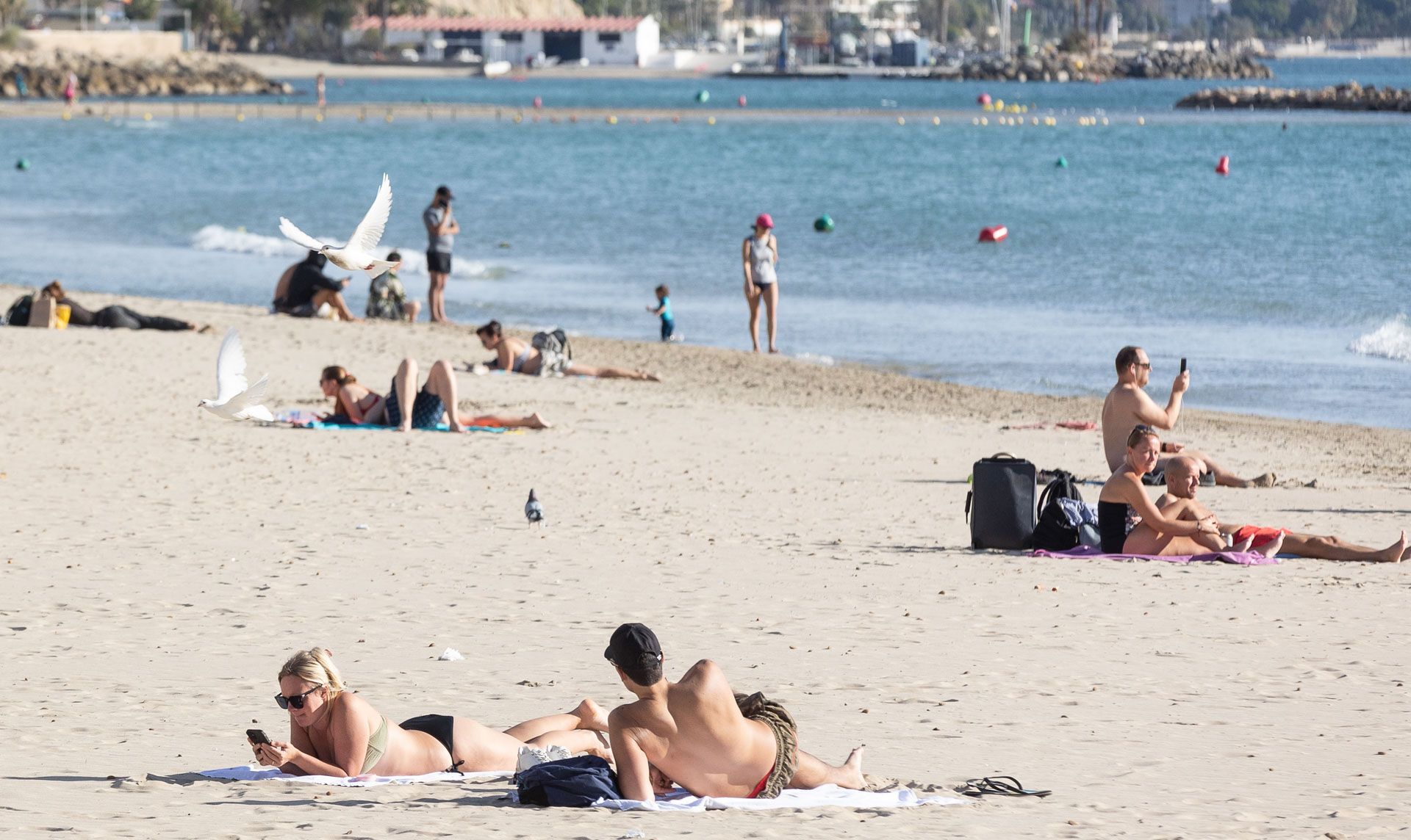 Numerosas personas disfrutan de un primaveral día en la Playa de El Postiguet
