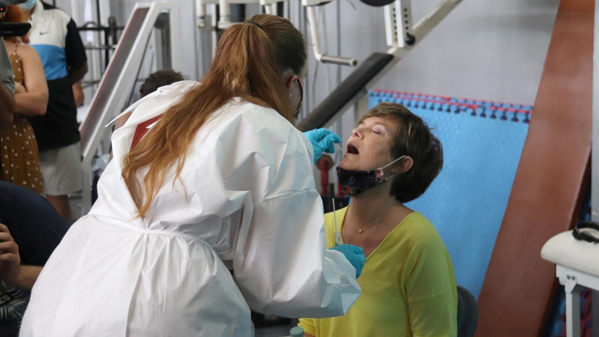 Pla general d&#039;una infermera extraient una mostra per fer una prova PCR a una turista