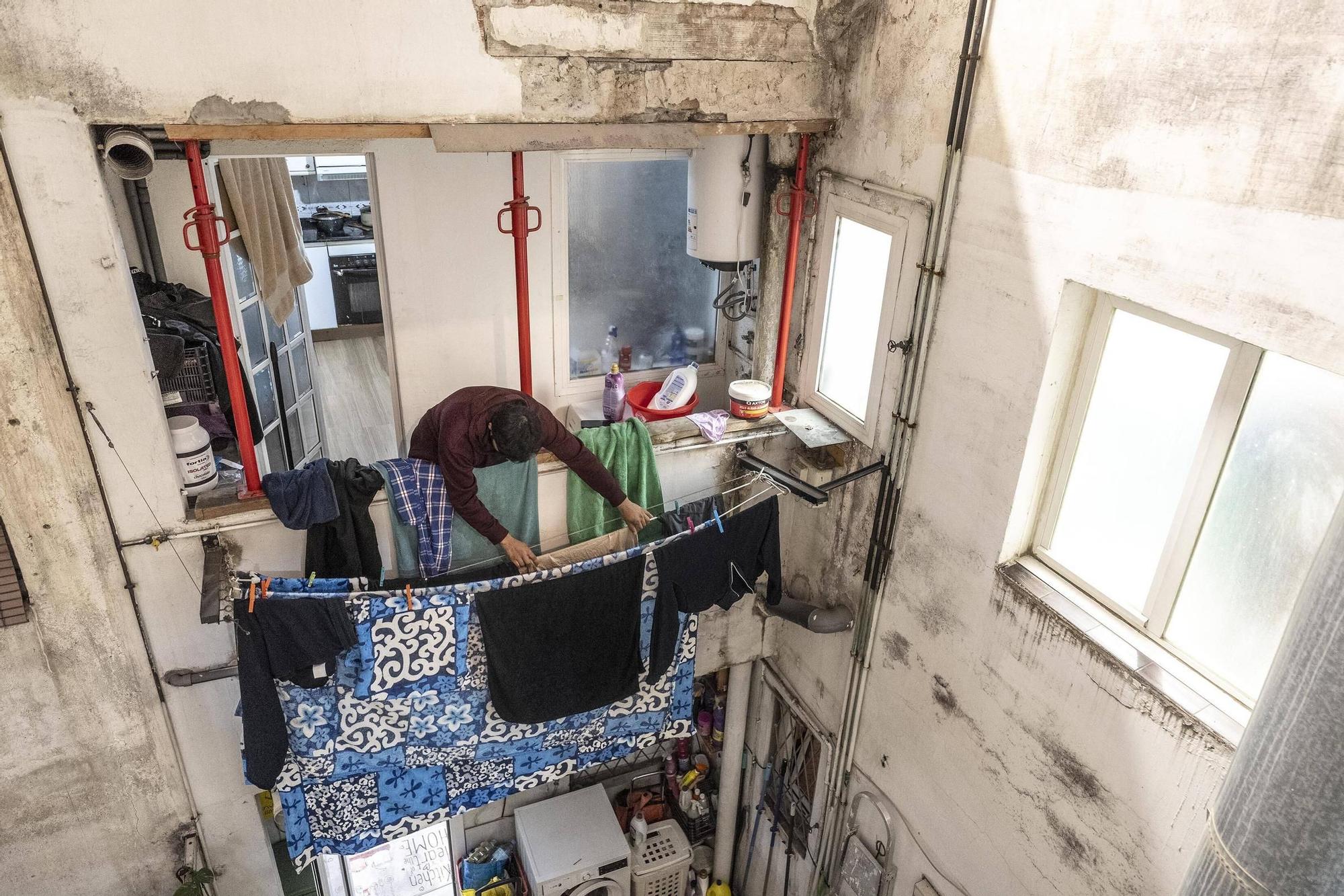 Un vecino de Trinitat Vella tiende la ropa en una ventana apuntalada en un edificio afectado por aluminosis, en Barcelona.