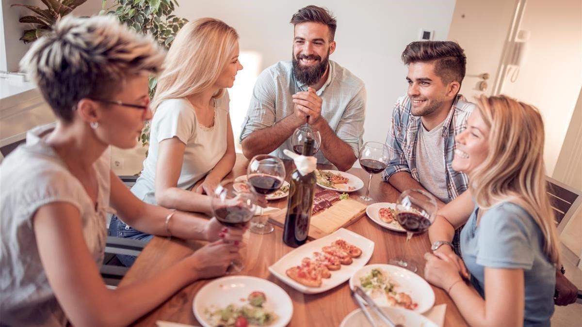 Un grupo de amigos conversa alrededor de la mesa, durante una comida.