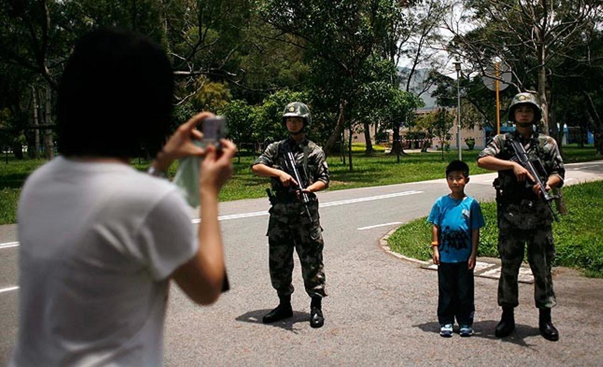 Una visitant fa una foto al seu fill amb dos militars en el dia de portes obertes de les instal·lacions a Hong Kong de l’Exèrcit d’Alliberament Popular.