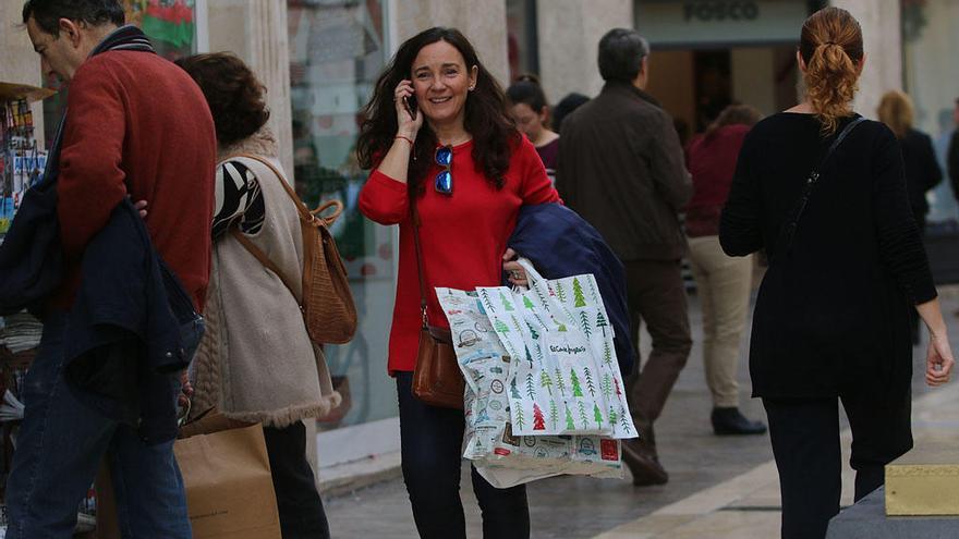 Una mujer pasea sonriente por la calle Larios.