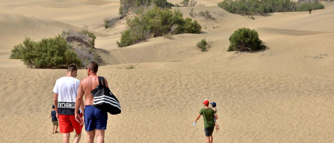 Imagen de archivo de turistas paseando por la reserva natural de las dunas de Maspalomas.