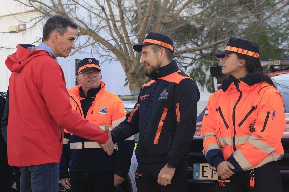 El presidente del Gobierno, Pedro Sánchez (i), conversa con miembros de Protección Civil durante su visita este viernes a las zonas afectadas por el temporal en Cádiz.