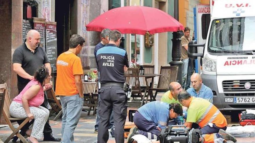 Los sanitarios atienden a la pequeña en plena calle y en presencia de la angustiada madre de la niña, que observa la operación sentada en una silla a la izquierda.