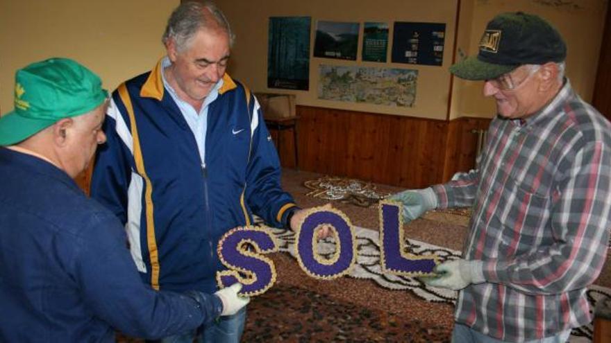 Pedro Villares, Dionisio Iglesias «Siso» y Jesús Fernández bromean con las letras preparadas creando la palabra «sol», que es lo que esperan para el domingo.