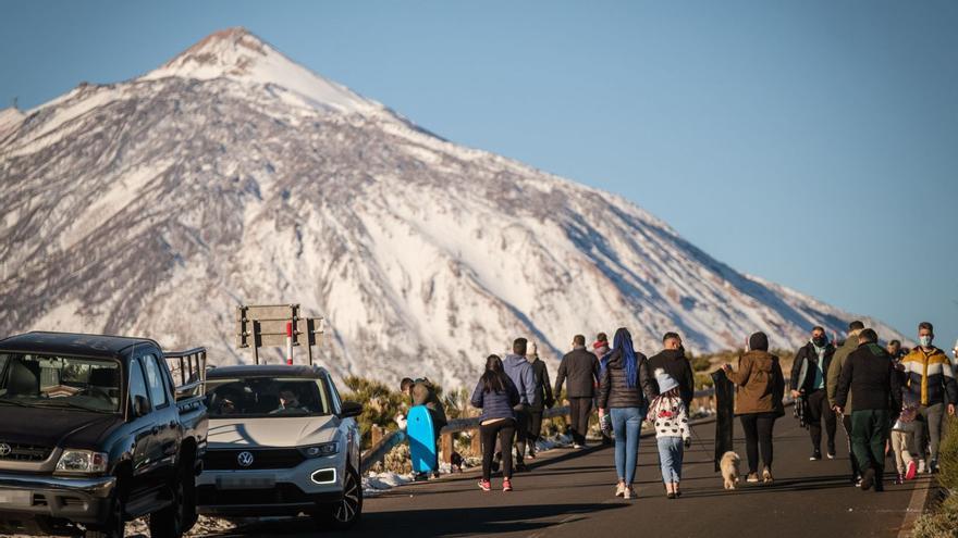 Vehículos en los márgenes de la carretera y un nutrido grupo de personas durante un día de nevada en el Parque Nacional del Teide.