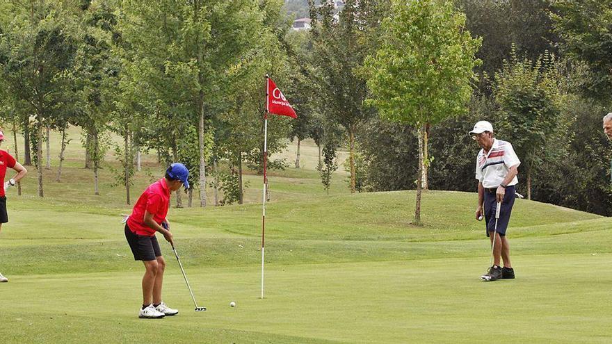 Yago Méndez Fernández patea en el hoyo 18 ante su abuela María del Mar Suárez. A la derecha, Justino Álvaro Redondo y Luis Fernández.