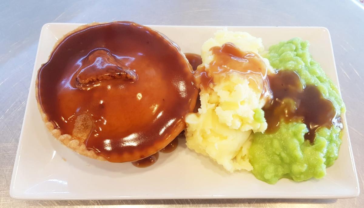 Pastel de carne con puré de patatas, guisantes y salsa, típica comida inglesa.