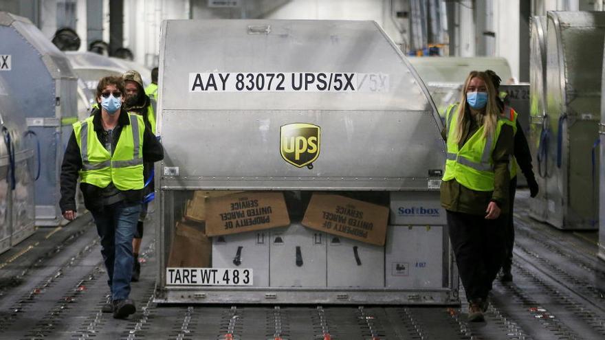 Empleados de UPS transportan un contenedor con las vacunas de Pfizer en Louisville (EEUU).