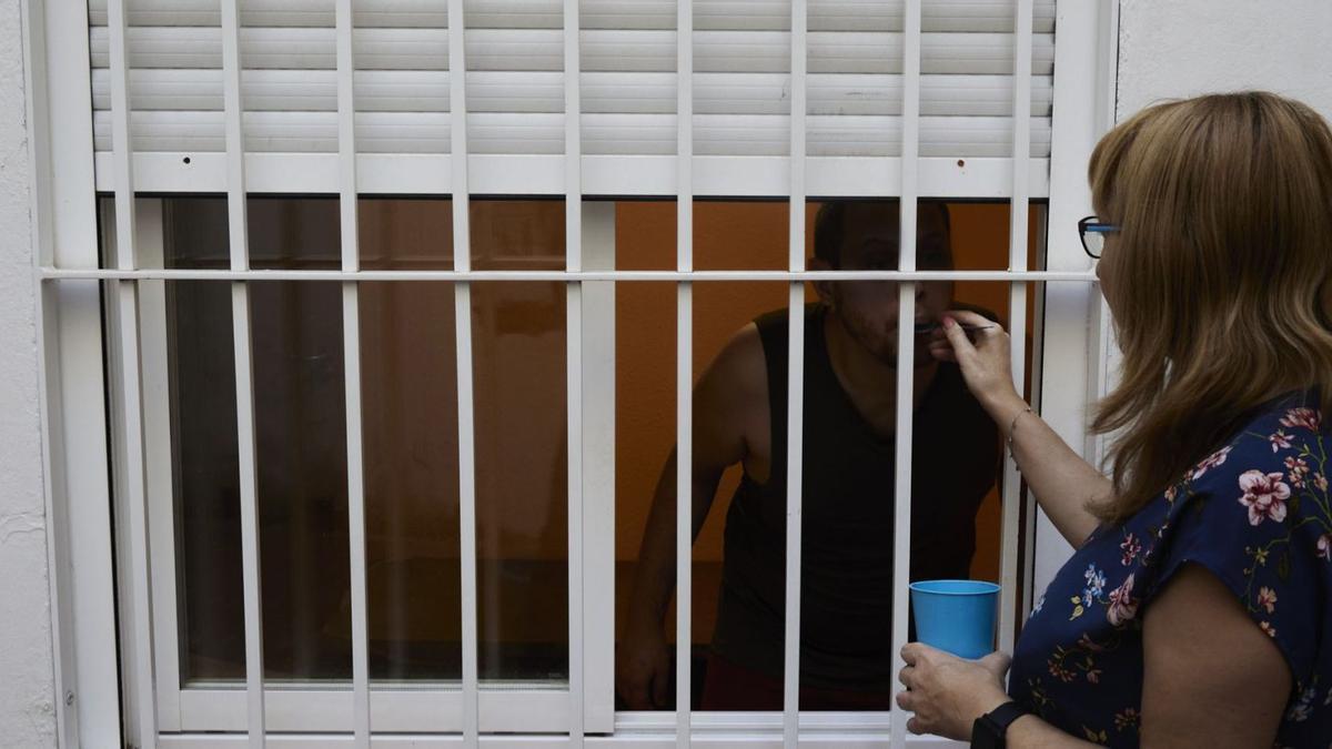 Carmen da la medicación a su hijo desde la ventana exterior.