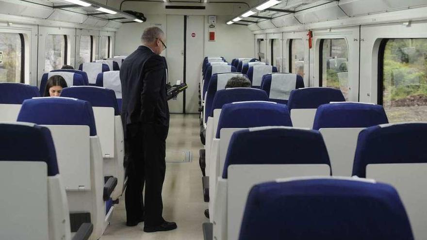 Un interventor comprueba los billetes de los pasajeros en un tren entre A Coruña y Ferrol.