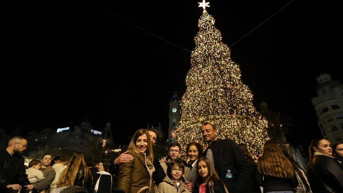 Una familia posando frente al árbol de Navidad de la Plaza del Ayuntamiento.