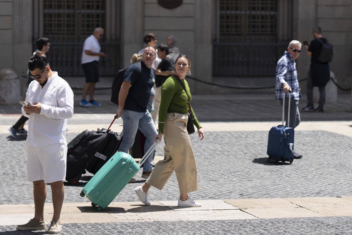 Turistes amb maletes a la plaça de Sant Jaume de Barcelona.