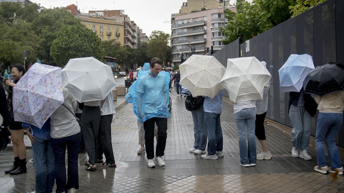 Turistas en Barcelona se protegen de la lluvia con paraguas.