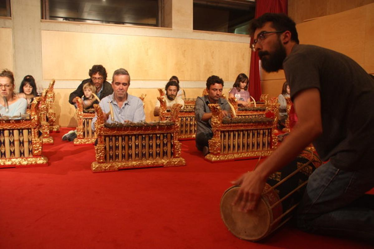 Un músic ensenya com es toca el gamelan als visitants del Museu de la Música.
