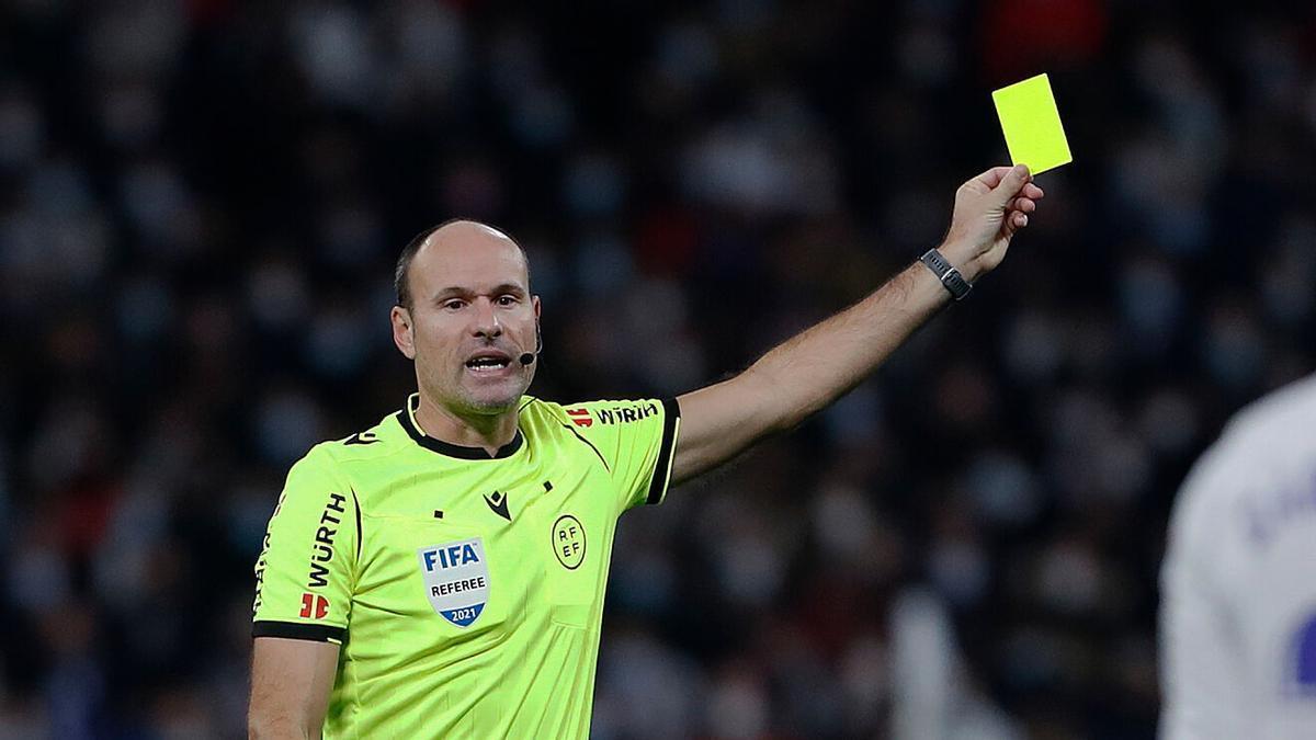 Mateu Lahoz enseña una tarjeta en un partido