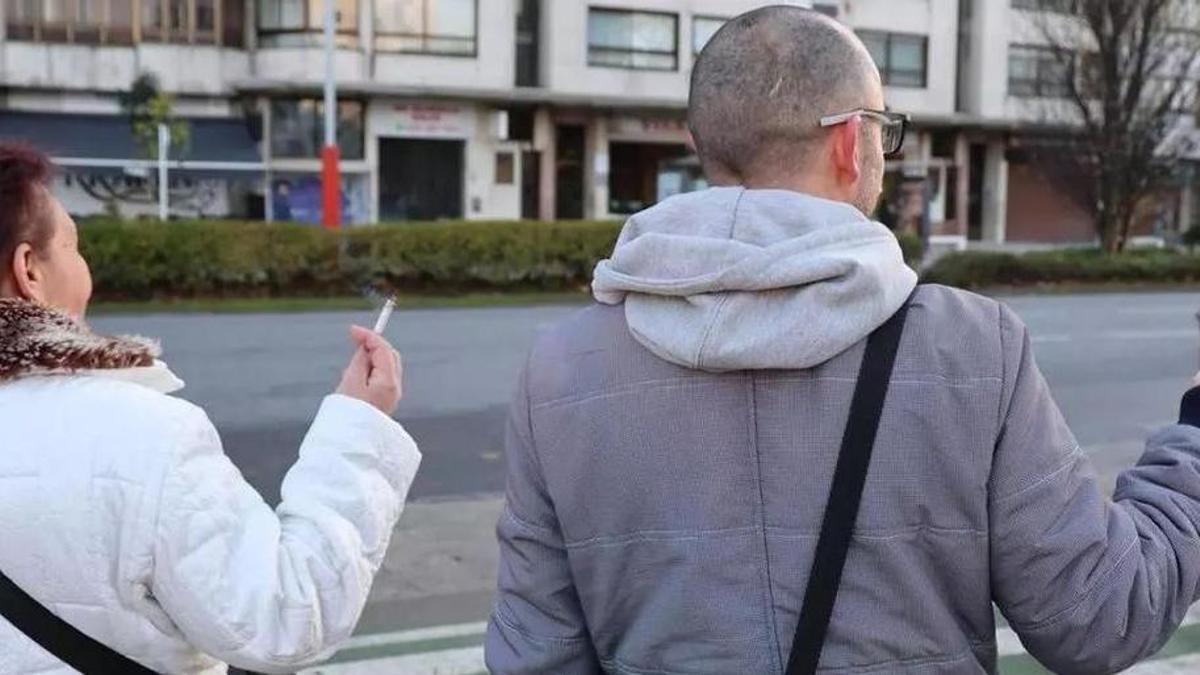 Dos personas fumando en una calle de Vigo.