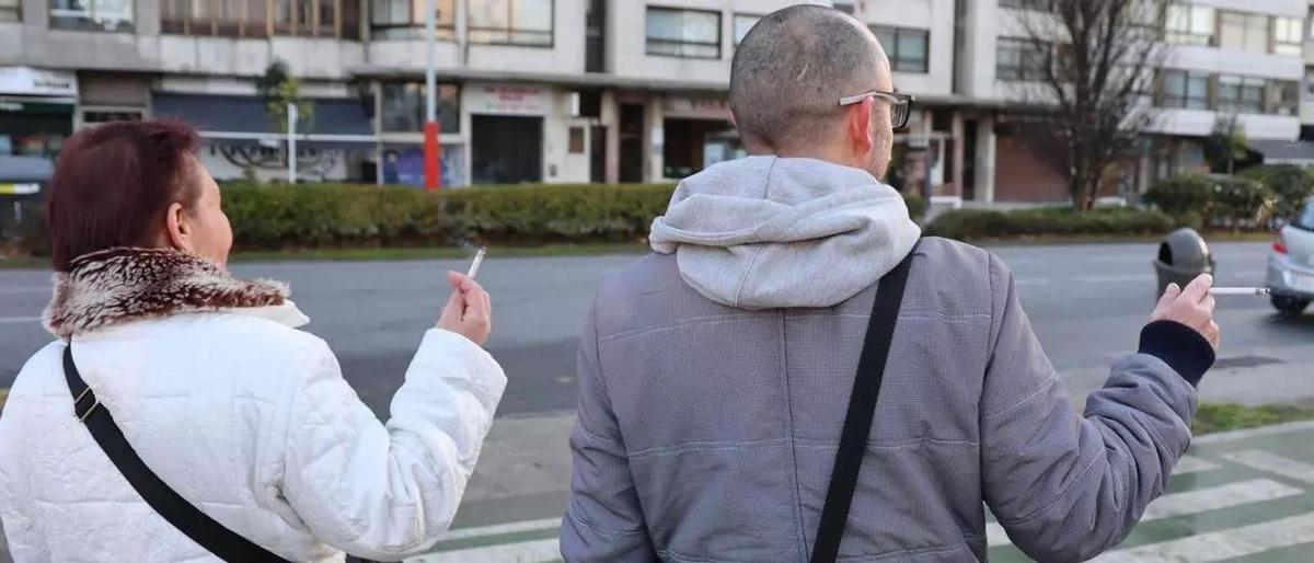 Dos personas fumando en una calle de Vigo.