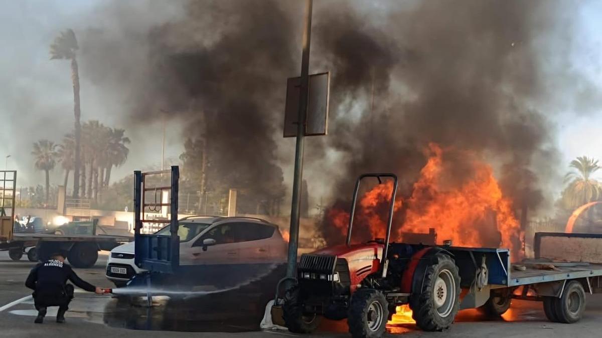 Un agente de la policía lanza agua con una manguera a la furgoneta en llamas.