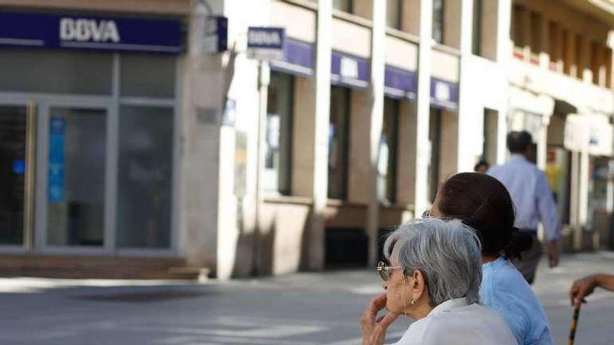 Unas mujeres, sentadas en un banco de la calle Santa Clara.