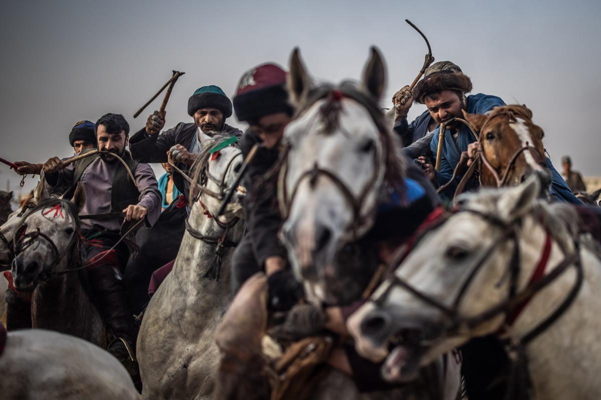 Jinetes afganos compiten en un deporte tradicional de Asia Central, en el que los jugadores montados a caballo intentan colocar una bolsa que se asemeja a un cadáver de cabra en una portería