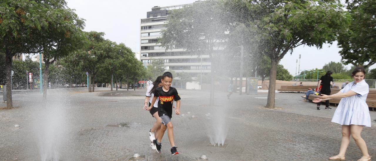 Niños juegan en las fuentes de Zaragoza para refrescarse.