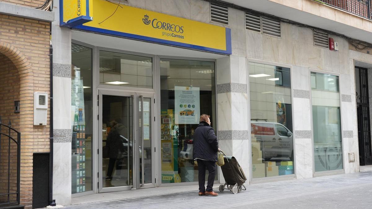 Una mujer camina delante de la oficina de Correos en Almassora, en una imagen de archivo.