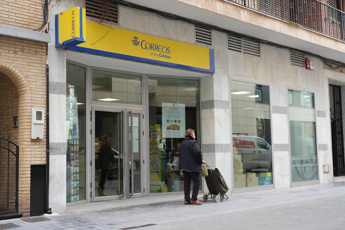 Una mujer camina delante de la oficina de Correos en Almassora.
