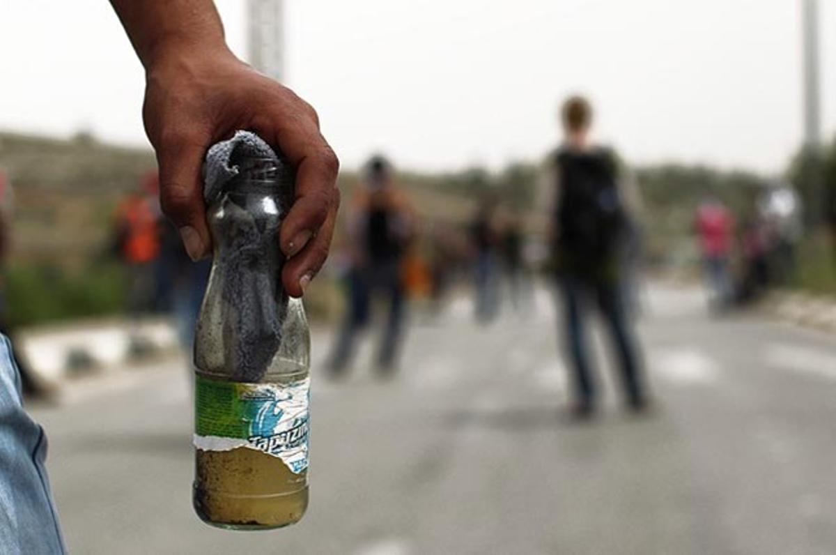 Un palestí porta un còctel molotov davant la presó militar israeliana a Bitwnia (Cisjordània).