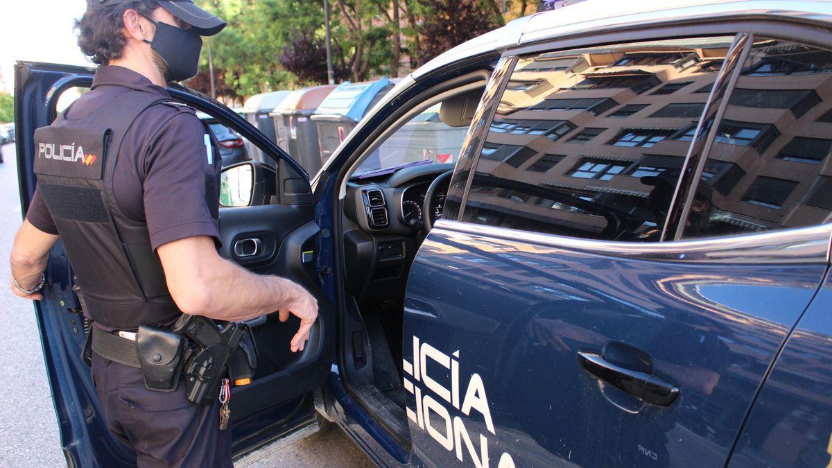 Un agente de la Policía Nacional junto a su coche patrulla.