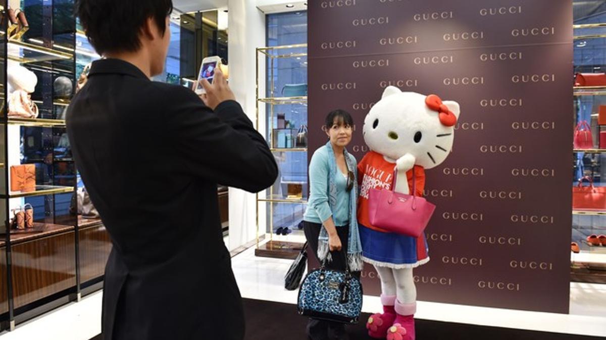 Visitantes de la tienda de Gucci en Tokio posan junto a Hello Kitty en su 40ª cumpleaños.