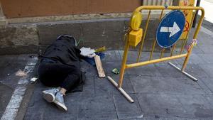 Un indigent dorm al mig del carrer a Barcelona.