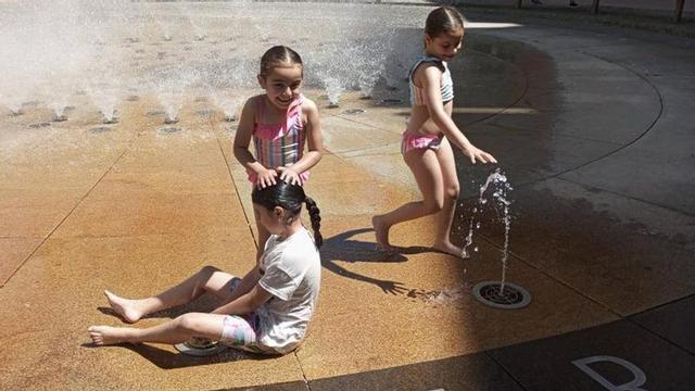 Tres niñas se refrescan en la fuente de la Glorieta de Compostela.