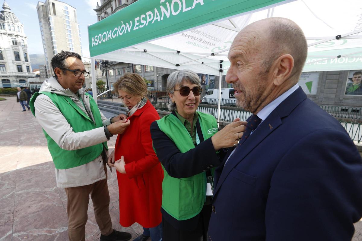 Yolanda Calero, presidenta de AECC en Asturias, coloca una pegatina al presidente de la Junta, Juan Cofiño.